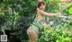 A woman in a green dress leaning against a fence.