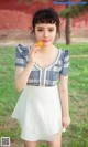 A woman in a white dress holding an orange in her hand.