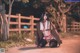 A woman in lingerie sitting on the ground next to a fence.