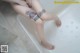 A woman sitting in a bathtub with a tattoo on her leg.