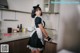 A woman in a maid outfit standing in a kitchen.