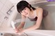 A woman is taking a bath in a bathtub with a shower head.