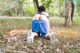 A woman sitting on the ground in the woods.