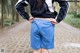 A woman in a black and white jacket and blue shorts standing on a dirt road.