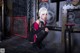 A woman in a black and red outfit crouching down in a room.