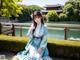 A woman in a blue kimono sitting on a bench.