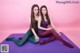 Two young women sitting on a purple yoga mat.