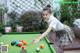 A woman is playing pool on a green table.