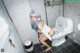 A woman with blue hair is sitting on a toilet.