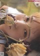 A woman laying on the ground with a bunch of flowers in her mouth.