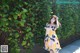 A woman standing in front of a wall covered in ivy.