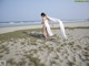 A woman in a white dress walking on a sandy beach.