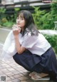 A young woman in a school uniform crouching on the ground.